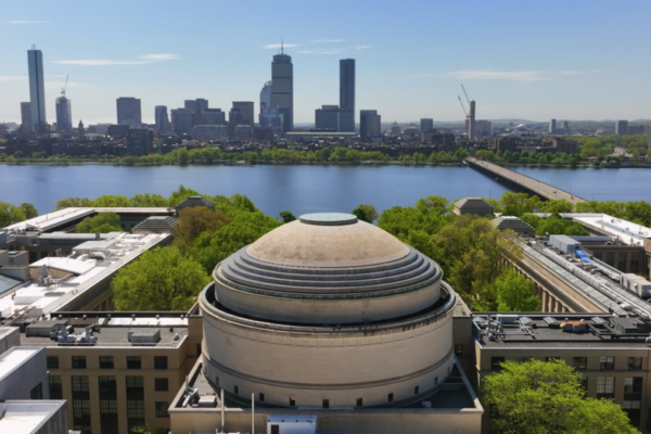 A large, domed building with a cityscape in the background. The dome has a circular base and a tall, rounded top. The cityscape includes tall skyscrapers and a river.