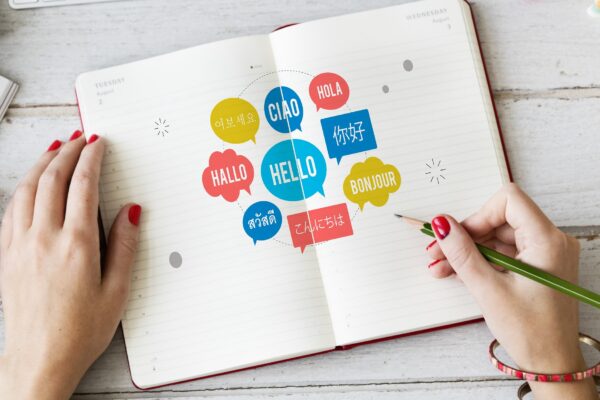 A woman engaged in writing, filling her notebook with the word "hello" in different languages, symbolizing her passion for language.