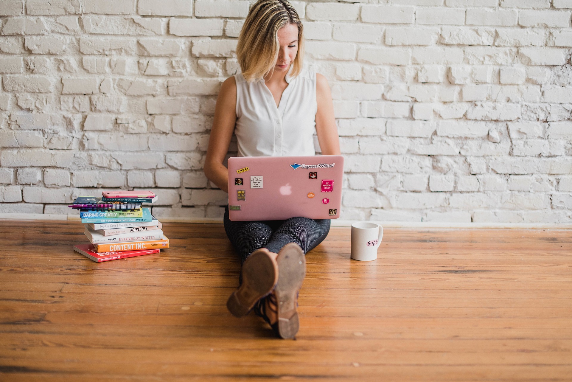 A woman seated on the floor, focused on her laptop, surrounded by a cozy and inviting atmosphere.