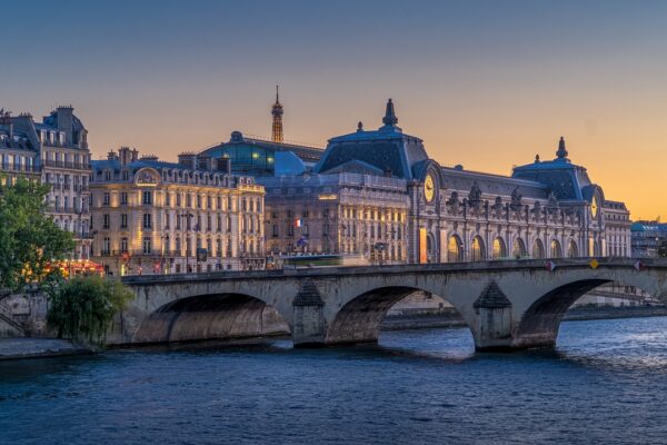 A river flows through Paris, with a bridge and multiple iconic buildings in view.