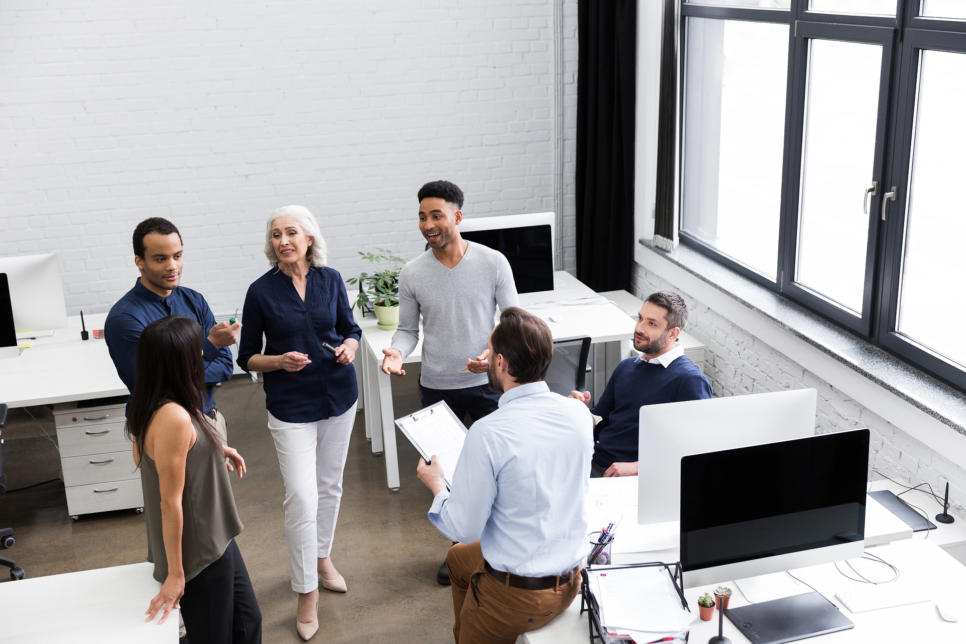 A team of individuals conversing in an office, highlighting interaction and professional engagement among coworkers.