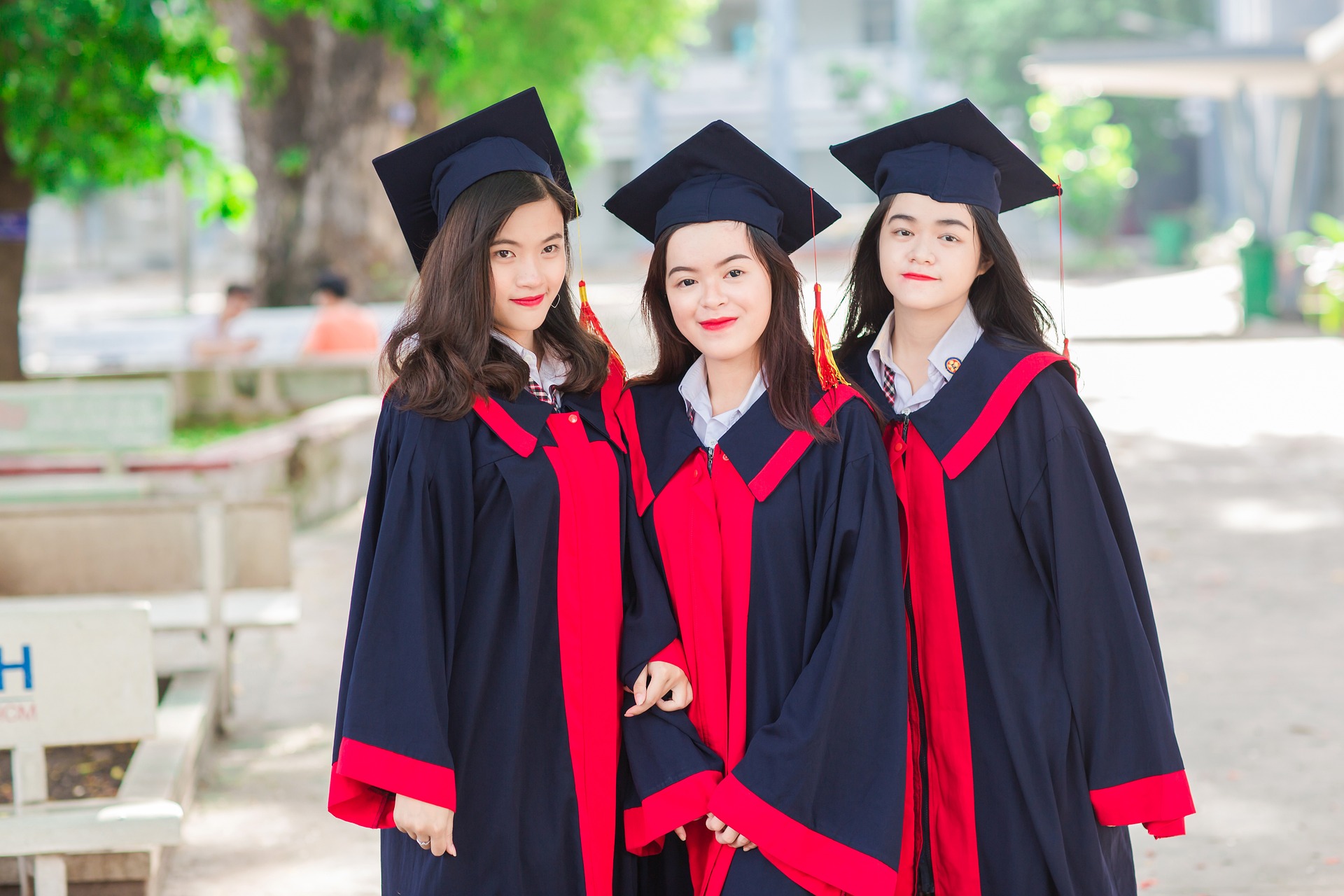 Three women in graduation gowns smiling and posing together for a celebratory photograph.